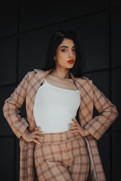 A woman wearing a white vest and brown plaid coat
